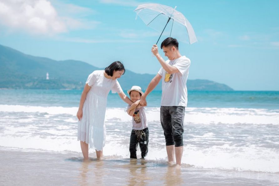 A joyful family enjoying a sunny day at Da Nang Beach, Vietnam, showcasing a heartwarming moment.